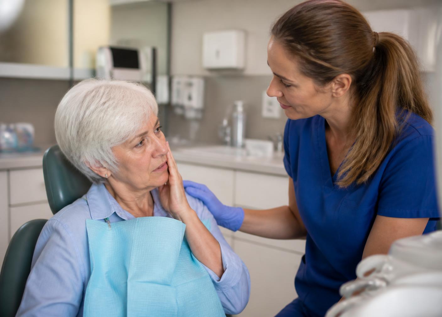 A dental assistant comforting a patient with tooth pain in the treatment room